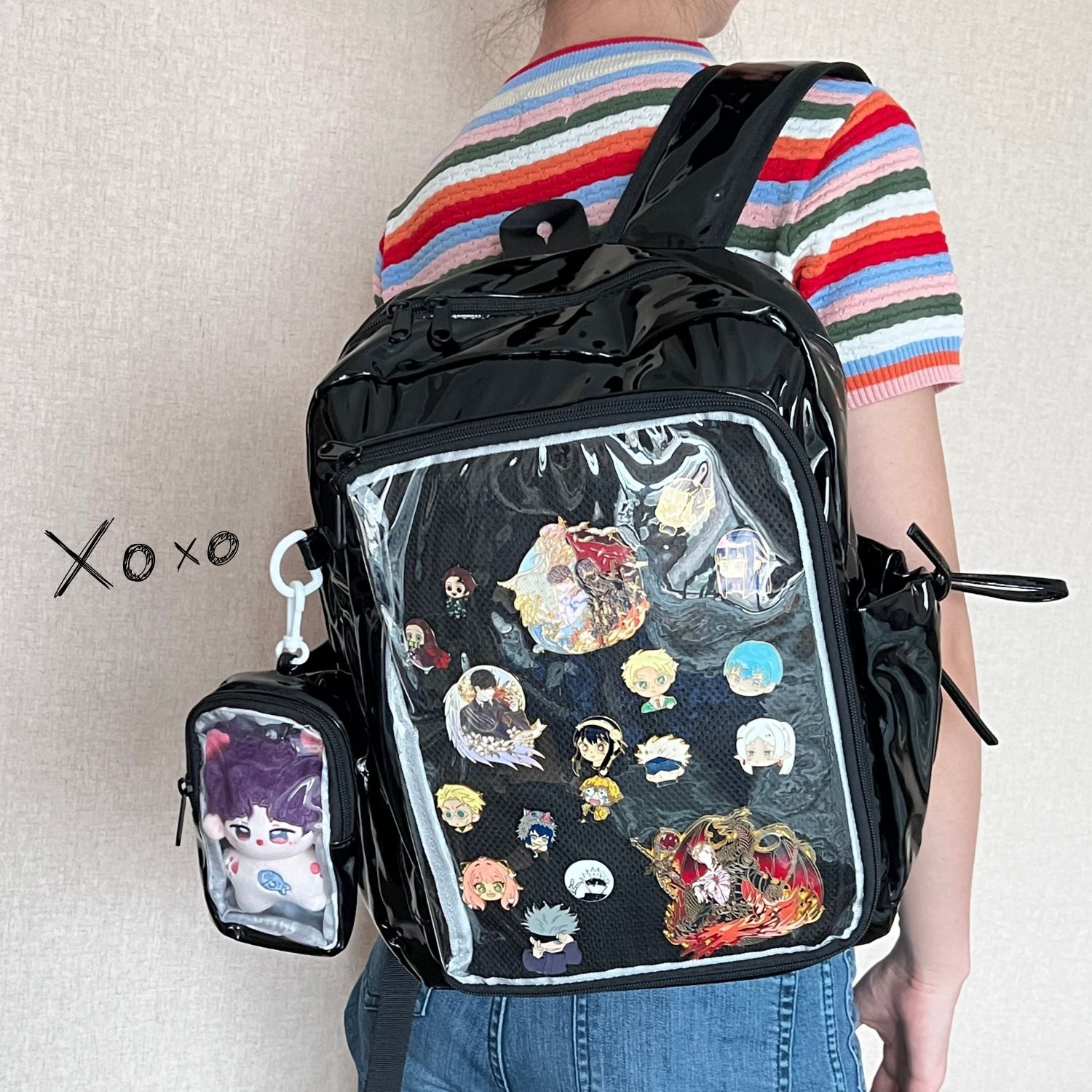 model wearing super large ita backpack decorated with enamel pins and plushie in clear window display
