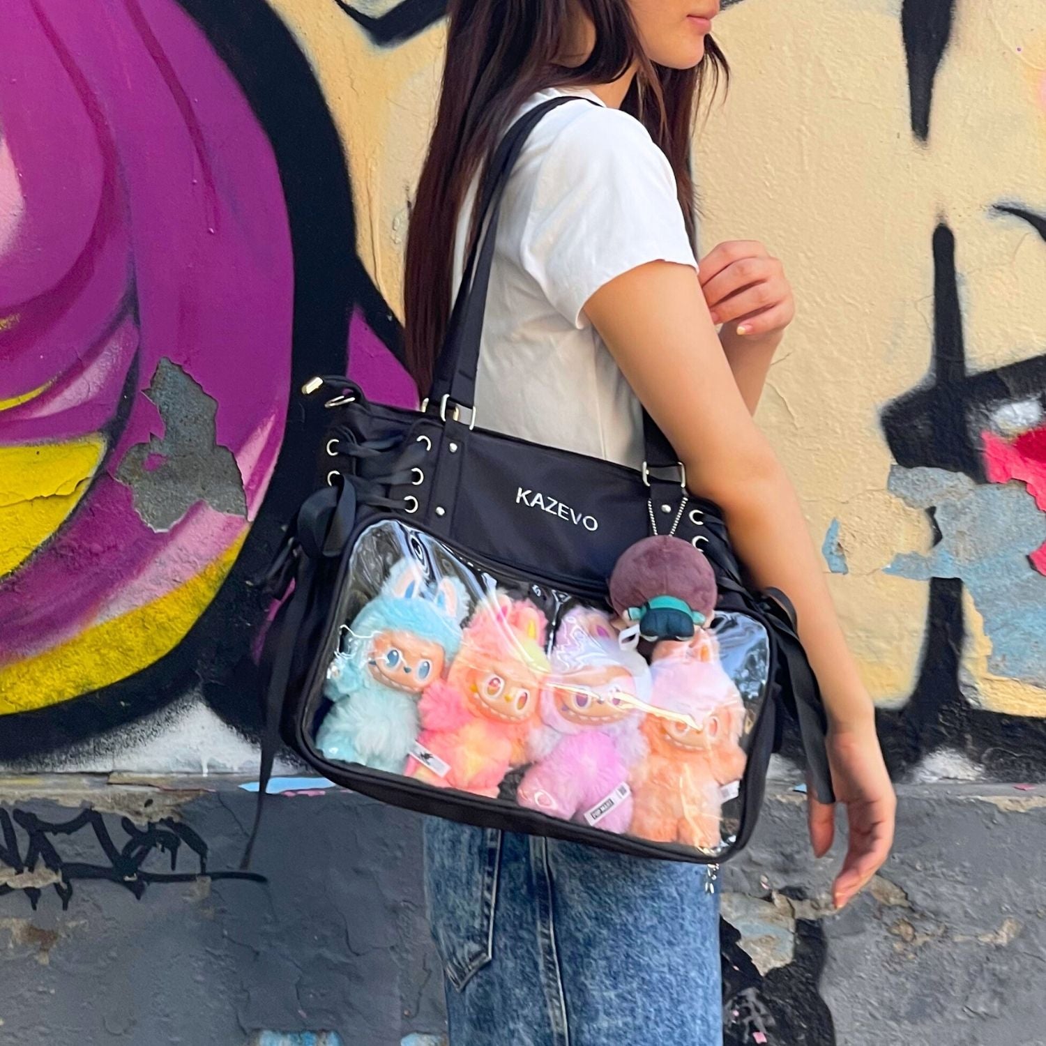 model carrying black ita bag on shoulder with Labubu plushies displayed through clear front window