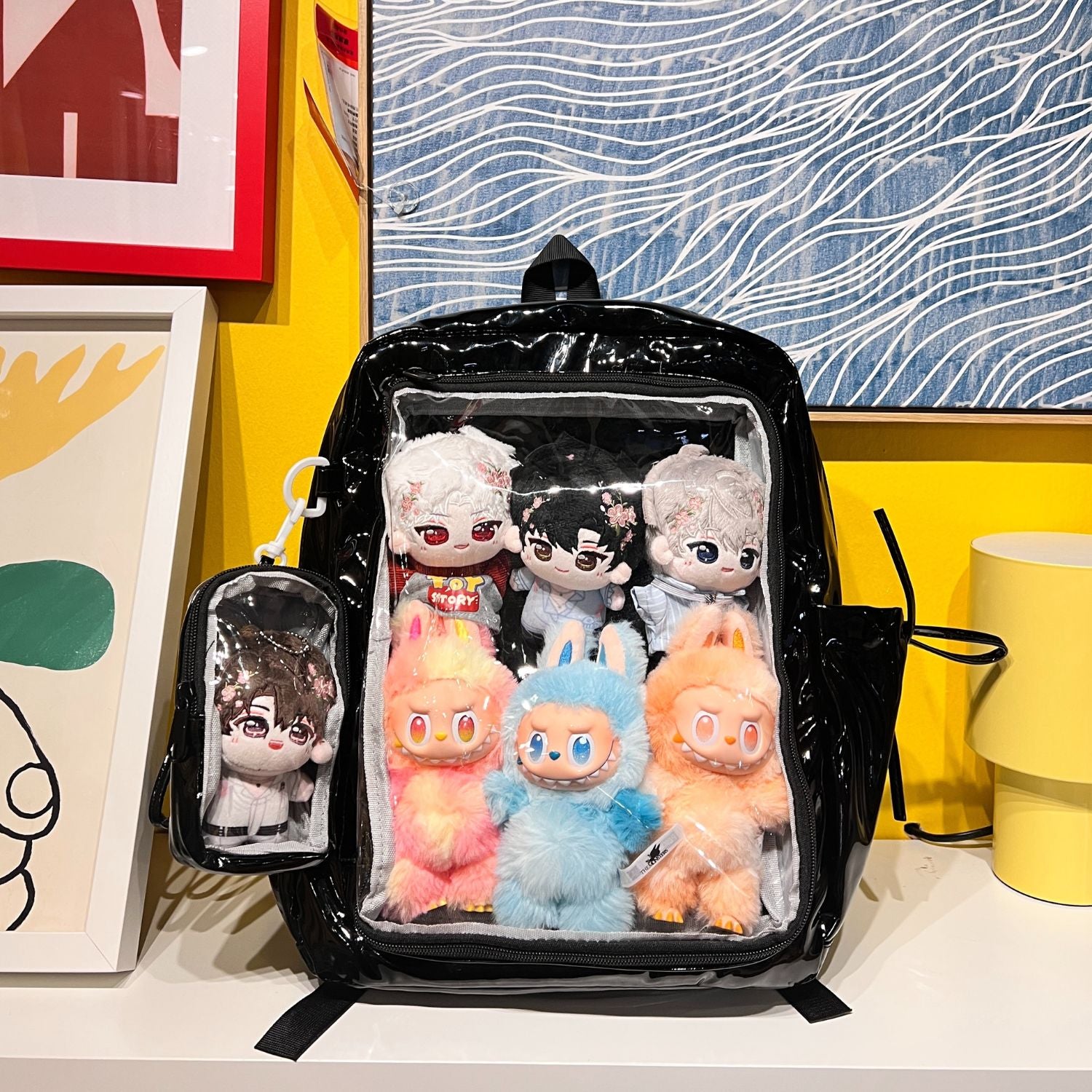 super large ita backpack on table showing Labubu plushie and anime plushie displayed in clear window