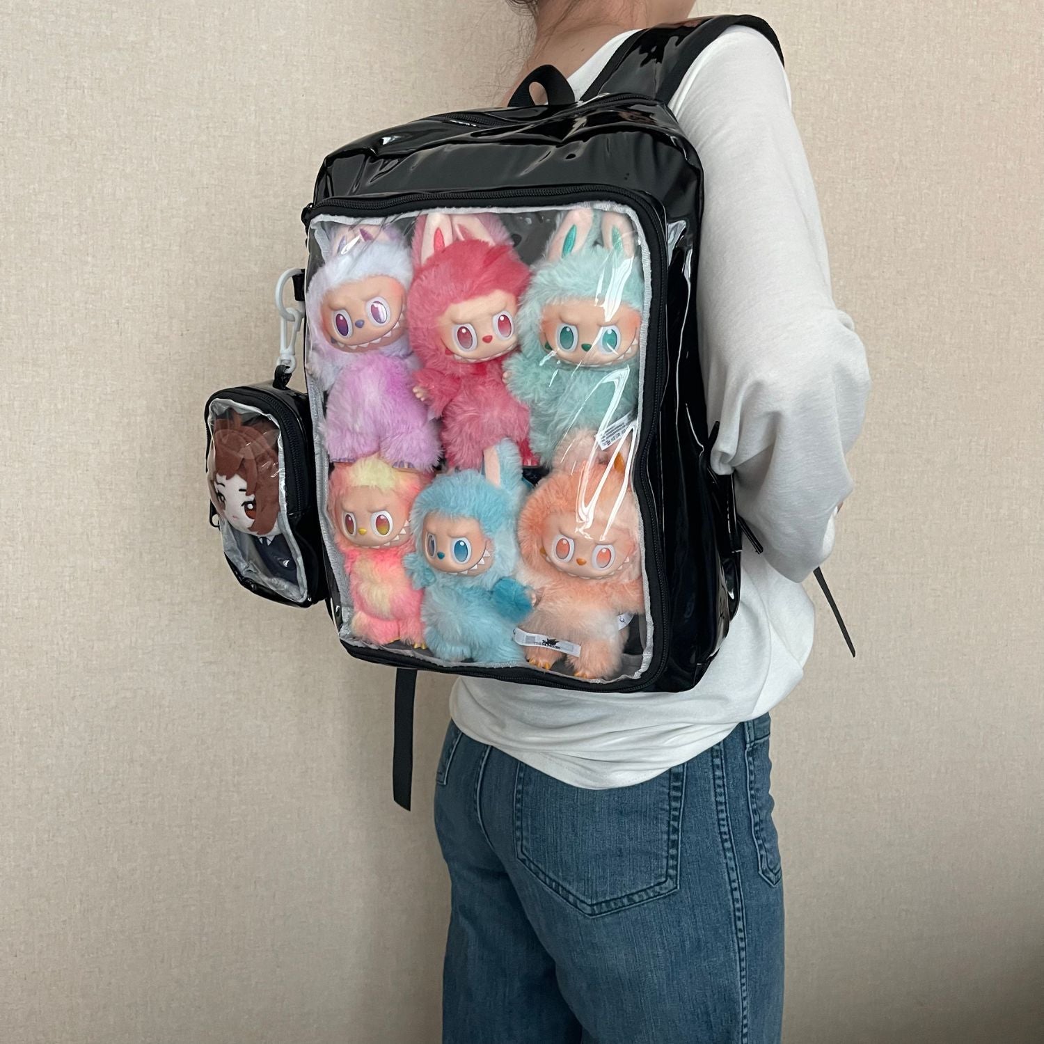 model wearing super large ita backpack with Labubu plushie and anime character plushie in display window