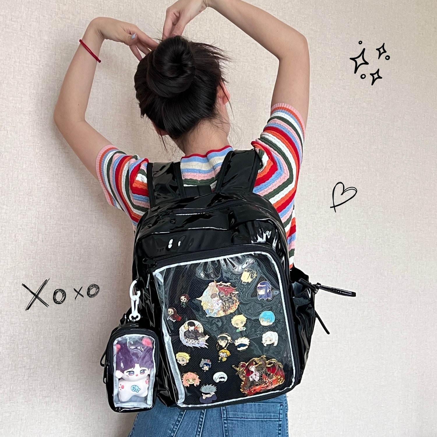 model wearing super large ita backpack decorated with enamel pins and plushie in clear window display